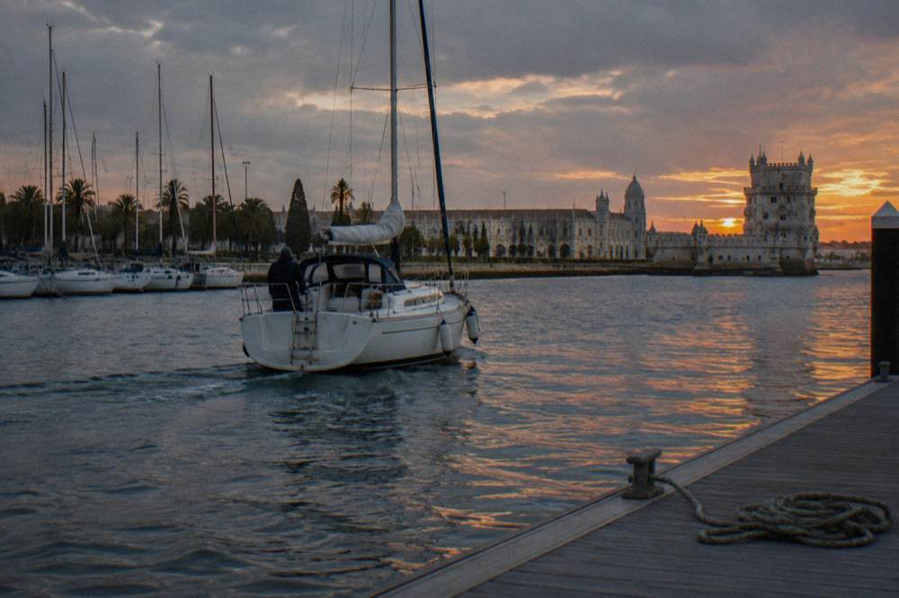 Sailboat on the Tagus river passing the Lisbon waterfront at dusk