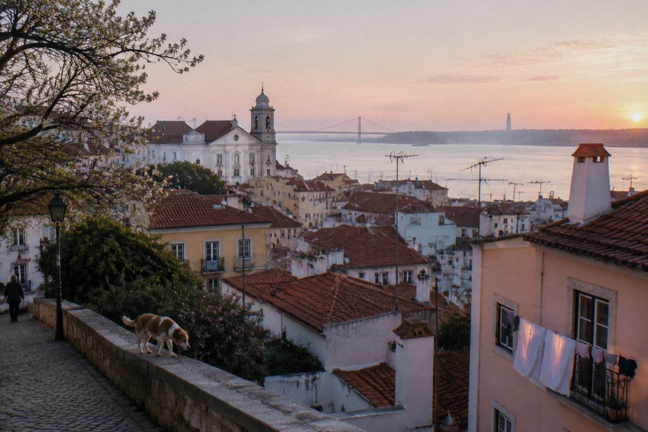 View over red rooftops of Alfama toward the Tagus River from a city viewpoint