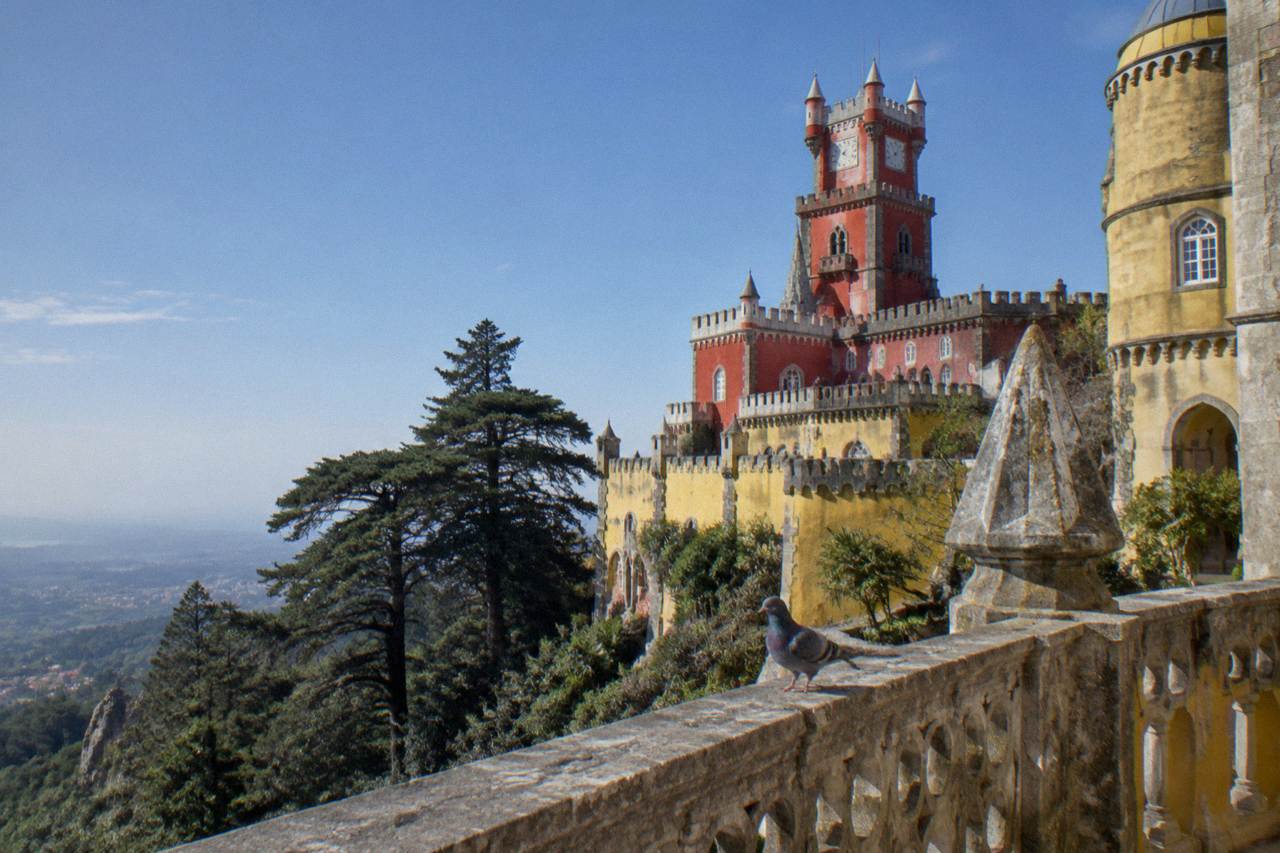 The colourful terraces and towers of Pena Palace above the Sintra hills under a clear sky